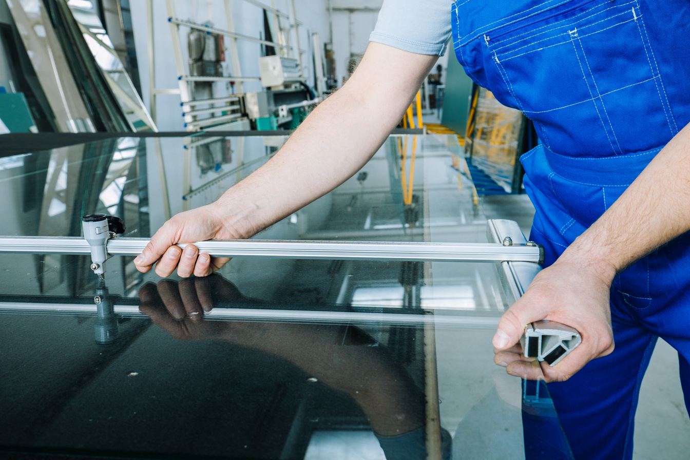 The glazier's worker cuts the glass with a special tool. Glassworks